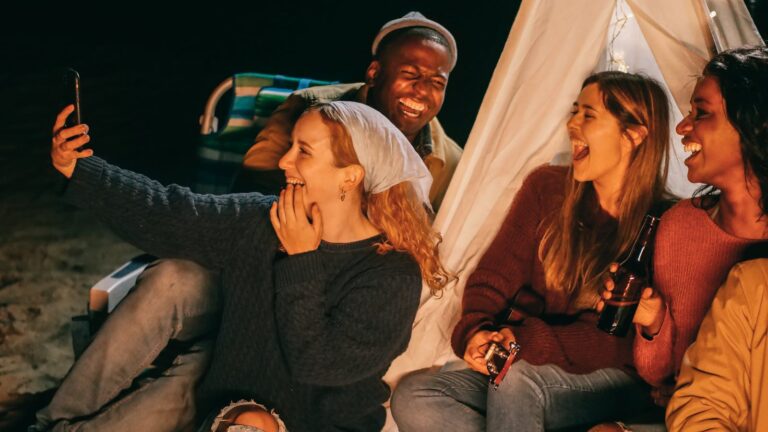 Radosna grupa przyjaciół uwiecznia wspomnienia podczas spotkania przy ognisku na plaży